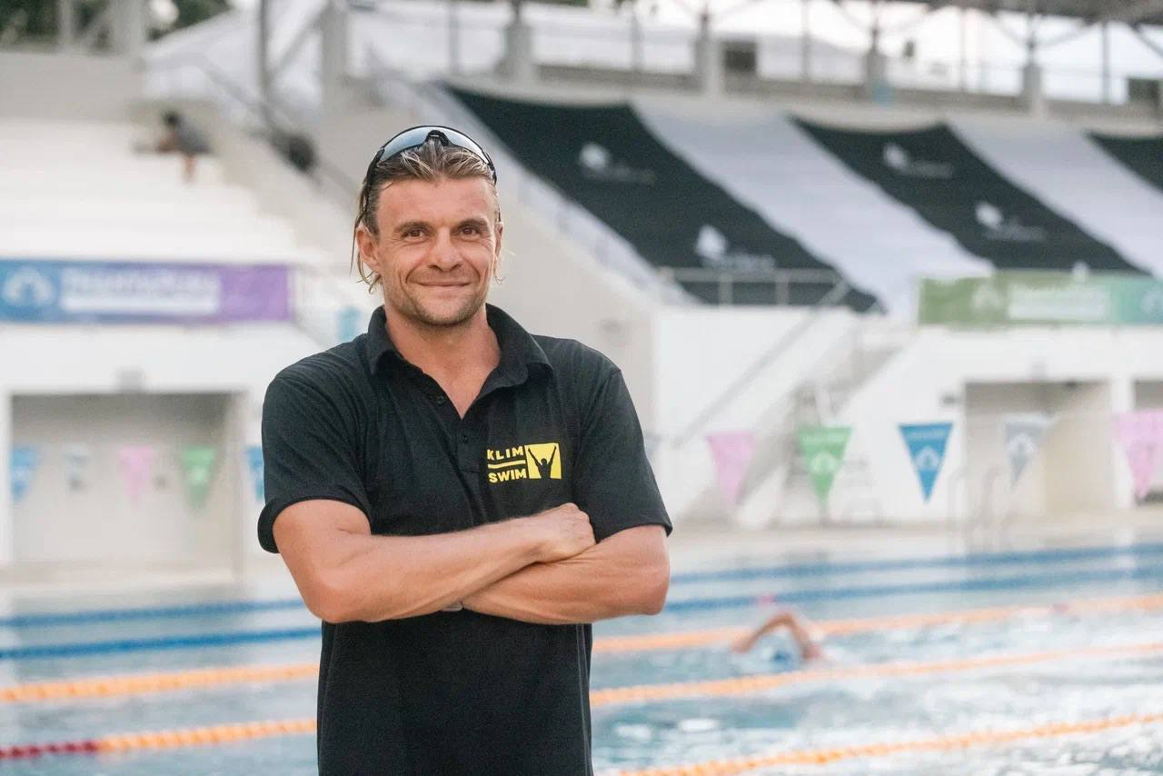 Alexander Taraskin standing with folded arms beside a swimming pool